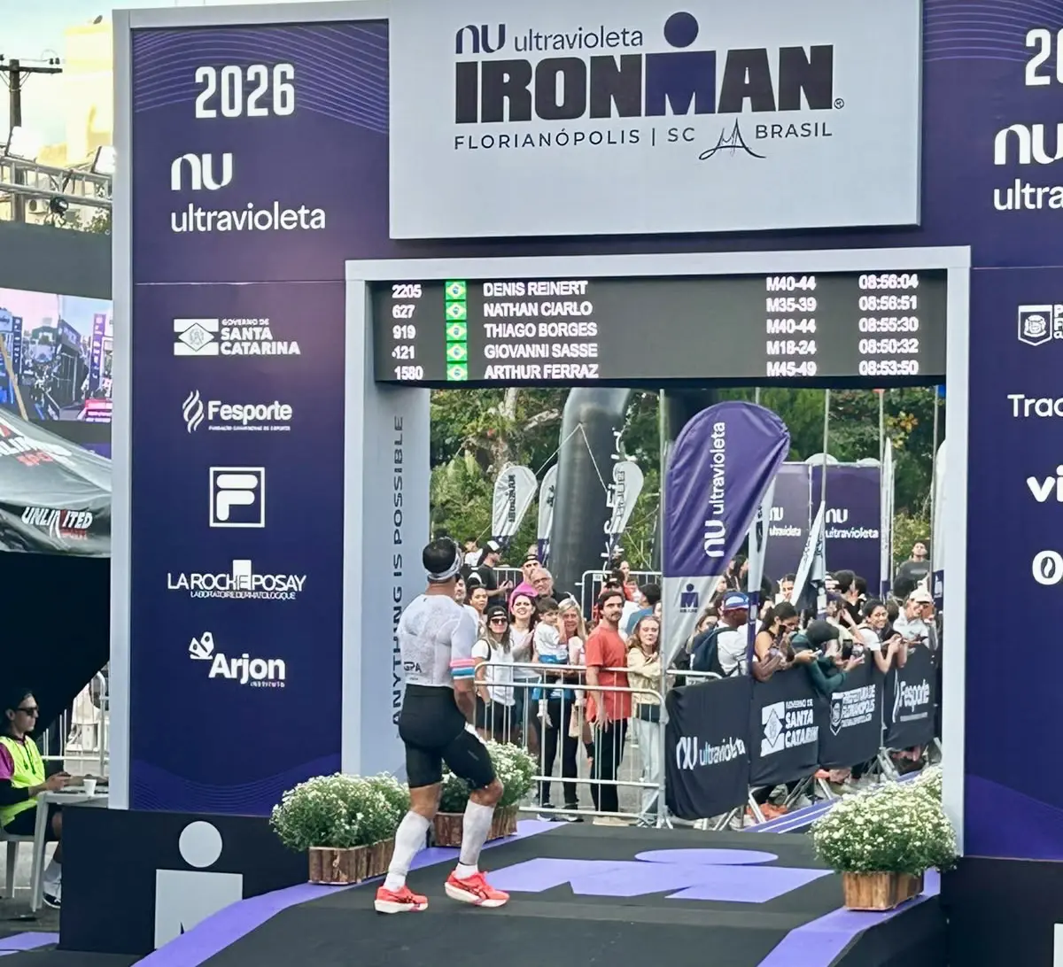 Dênis cruzando a linha de chegada do Ironman Florianópolis 2026